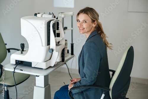 Smiling woman patient awaits a vision test at opticians shop or ophthalmology clinic