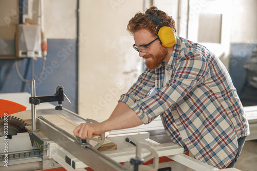 Woodworker sawing a board with a circular saw in a carpentry workshop. High quality photo
