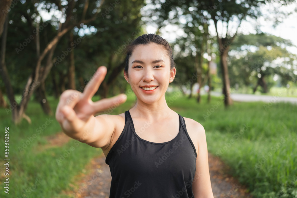 Young Asian woman gives two thumbs up to encourage herself before going for a weight loss run. Young Asian woman gives two thumbs up to encourage herself before going for a weight loss run.