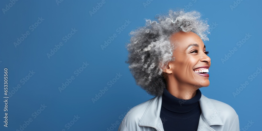 Photo on blue background with copy space. Psychology portrait of a confident beautiful African American woman in her 50s. Middle-aged woman with a short gray hair looking by side. Photo on blue background with copy space. Psychology portrait of a confident beautiful African American woman in her 50s. Middle-aged woman with a short gray hair looking by side.