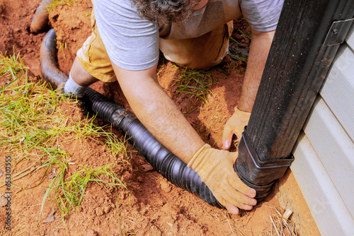 Фотография Man installing flexible gutter extension drainage pipe connector downspout with