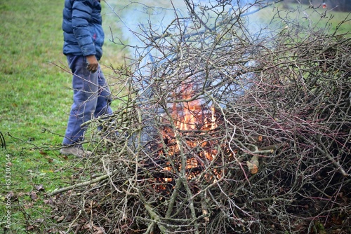 
A gardener burns waste branches in a garden in a village traditionally

