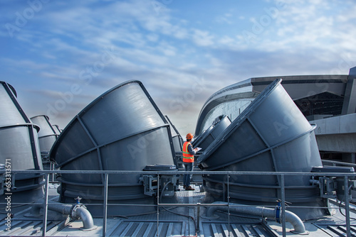 worker open valve of cooling tower on blue sky background. worker opening butterfly valve on top of cooling Tower. worker check valve on cooling tower. photo