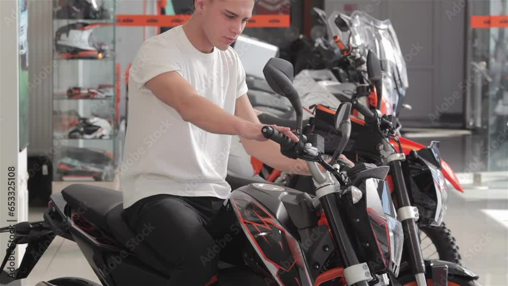 Young man sitting on motorcycle and examining it Young man sitting on motorcycle and examining it