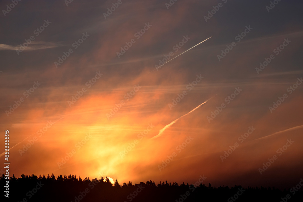 Sunrise over the forest. Beautiful sky with traces of airplanes Sunrise over the forest. Beautiful sky with traces of airplanes