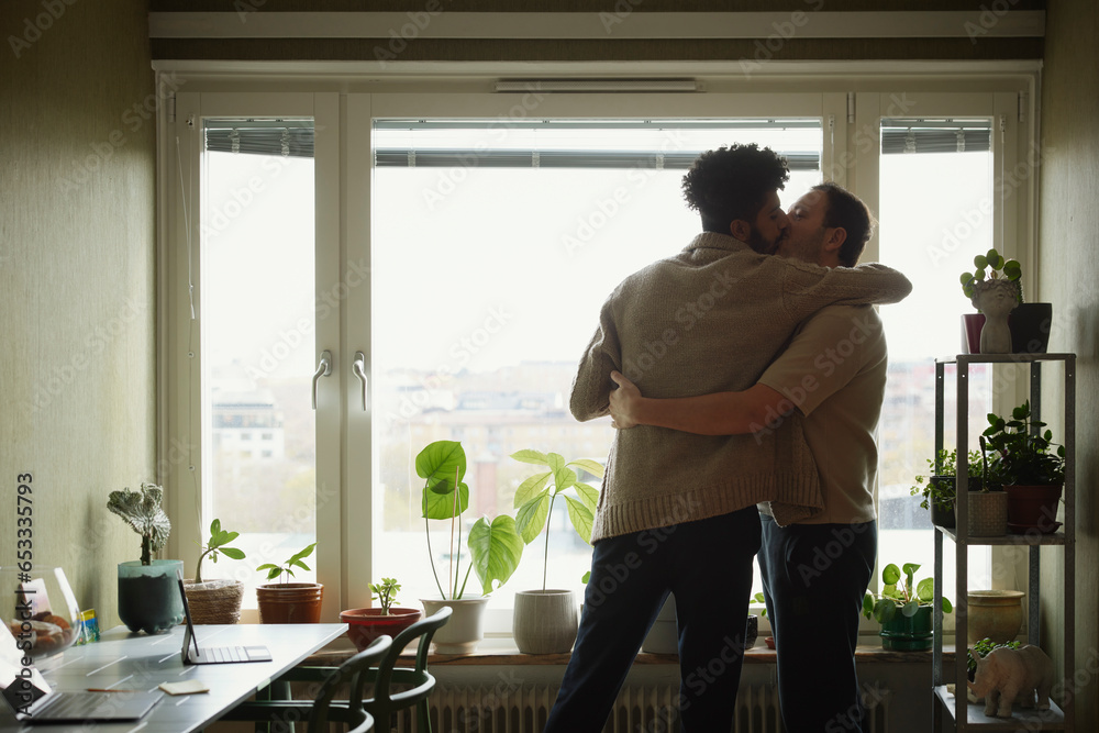 Homosexual couple standing with arms around and kissing Homosexual couple standing with arms around and kissing