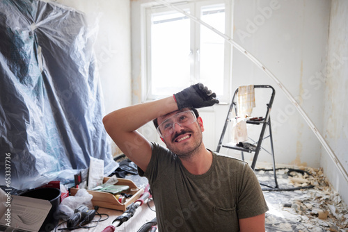 Man in protective eyeglasses renovating room at home photo