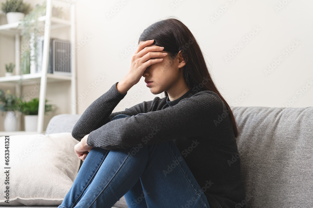 Unhappy anxiety young Asian woman covering her face with pillow on the cough in the living room at home. Unhappy anxiety young Asian woman covering her face with pillow on the cough in the living room at home.