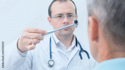 A neurologist examines the nervous system and reflexes of a male patient with a neurological hammer in a medical clinic. Neurological examination.