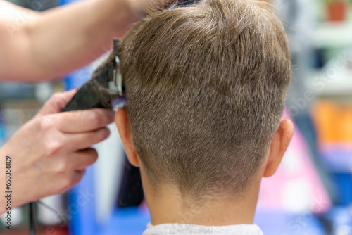Hair cutting for a child using a hair clipper in a beauty salon