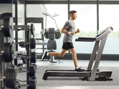 Full length profile shot of a guy training on a treadmill