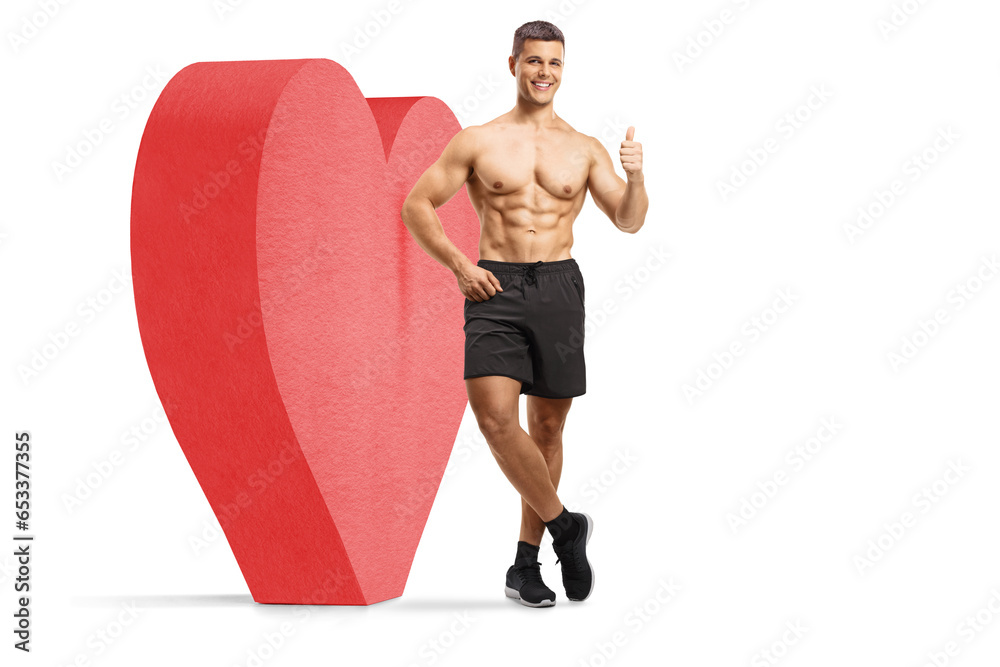 Shirtless young man leaning on a red heart and showing a thumb up sign Shirtless young man leaning on a red heart and showing a thumb up sign
