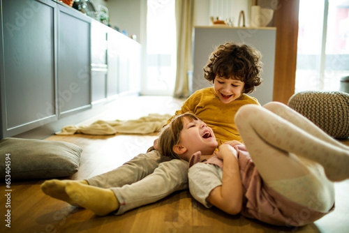 Young brother and sister playing together in the living room at home