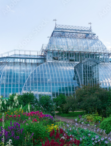 view of the Saint Petersburg Botanical Garden with flower beds and anсient palm greenhouse in the background