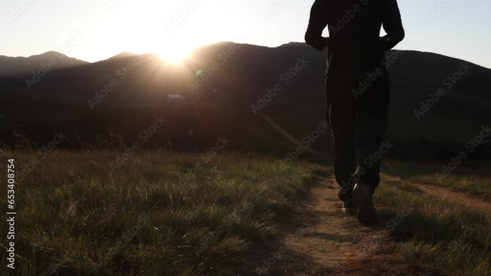 Homem caminhando com celular na mão, na natureza