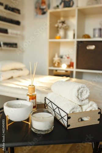 Cosmetic products for spa treatments on a wooden table. In the foreground a towel, candles and aroma oils.