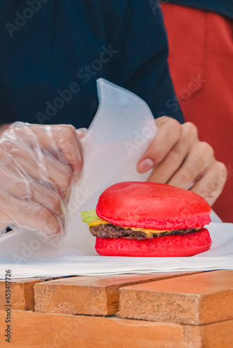 Individual red burgers that will be wrapped in white paper (ID: 653417726)