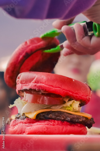 red burger with blur background of burger and tongs (ID: 653417744)