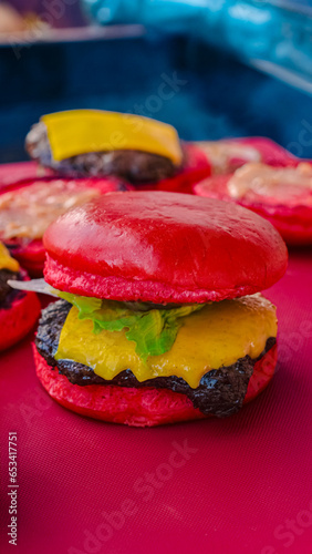 red burger filled with vegetables, meat and cheese with a blurred burger background (ID: 653417751)
