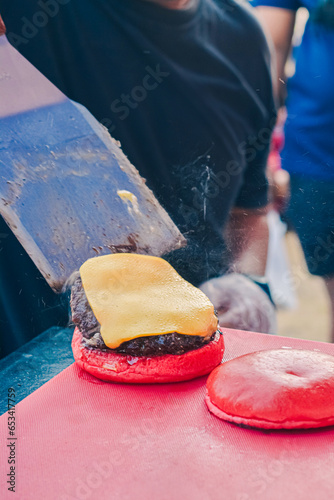 Half a red burger filled with meat and cheese is poured into a mold using a spoon (ID: 653417759)