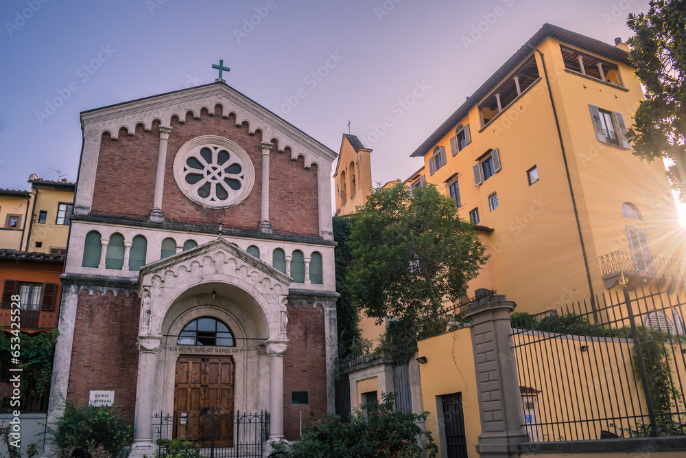 Facade of a Lutheran church in Florence in medieval style with rose window in low light with sun rays, ITALY