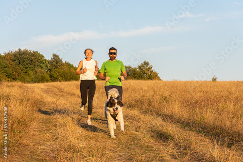 fitness  sport  people and lifestyle concept - happy couple with dog running outdoors © VSzili