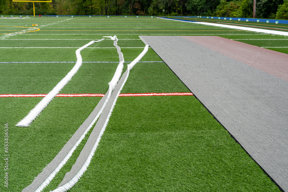 Synthetic turf field under construction with lines and graphics being installed.	