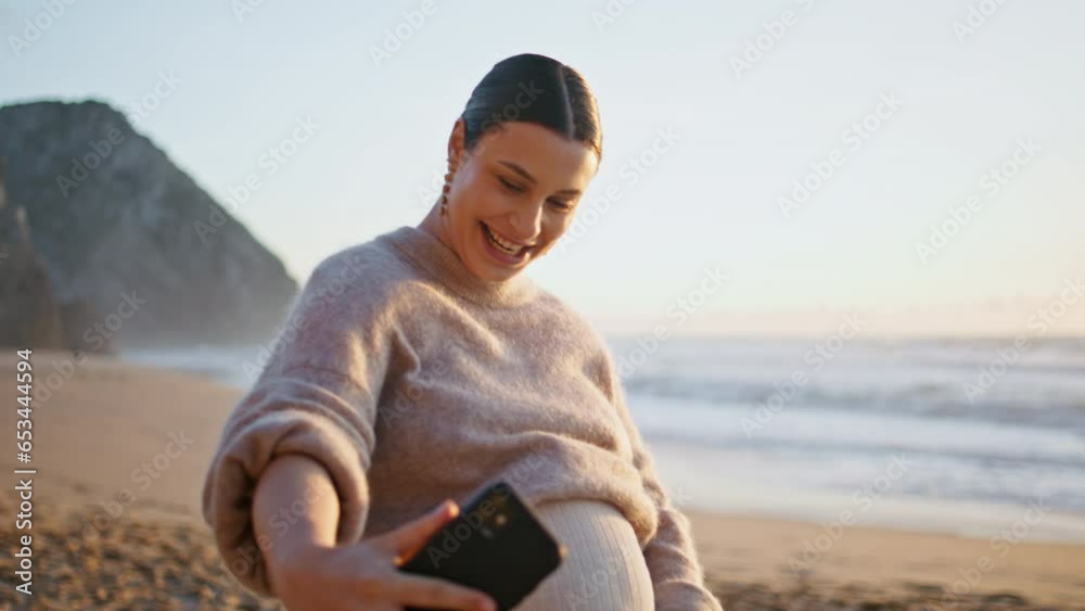 Pregnant woman video blogging on smartphone walking at sandy coast close up. Pregnant woman video blogging on smartphone walking at sandy coast close up.