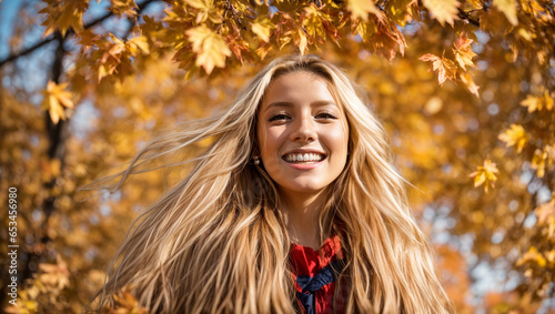 Portrait of a beautiful happy girl with long hair on a background of autumn leaves
