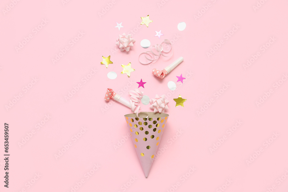 Composition with party hat, whistles and confetti on pink background