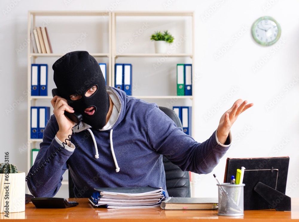 Male thief in balaclava in the office Male thief in balaclava in the office