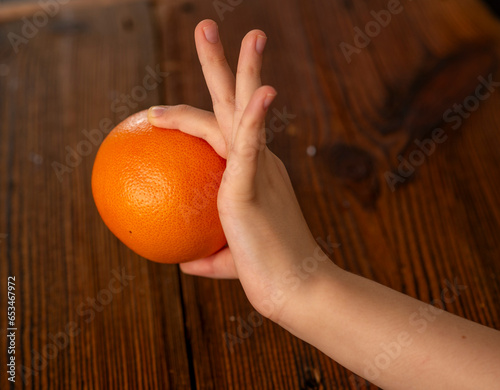 childish hands holding an orange over the table photo