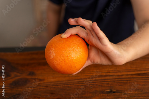 childish hands holding an orange over the table photo