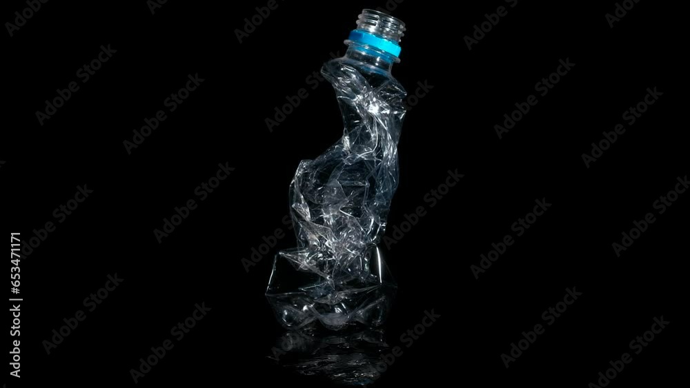 Wrinkled plastic bottle on black. A view of wrinkled plastic bottle spinning on the black. A concept of eco trouble and Earth pollution. Wrinkled plastic bottle on black. A view of wrinkled plastic bottle spinning on the black. A concept of eco trouble and Earth pollution.