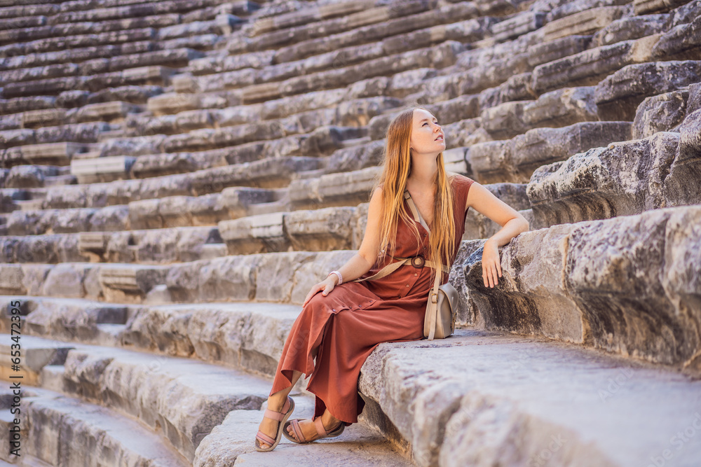 Fototapeta premium Woman tourist explores Aspendos Ancient City. Aspendos acropolis city ruins, cisterns, aqueducts and old temple. Aspendos Antalya Turkey. turkiye