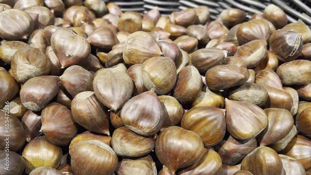 Edible chestnuts in a store. Dark and light brown colored. Selective focus. Close-up. Camera slowly rotating to left. Edible chestnuts in a store. Dark and light brown colored. Selective focus. Close-up. Camera slowly rotating to left.