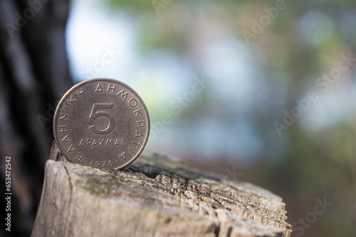 Greek five drachmes coin on natural wooden log background photo