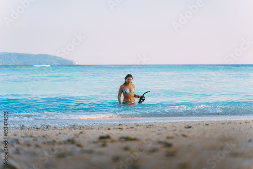 fit girl leaving the beach with a snorkel in her hand