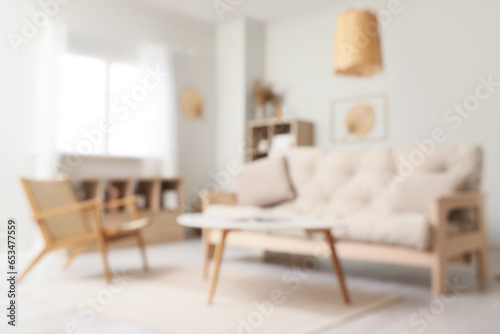 Blurred view of living room interior with white sofa, armchair and coffee table