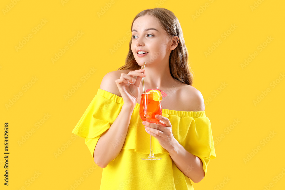 Beautiful young woman with glass of tasty aperol spritz cocktail on yellow background Beautiful young woman with glass of tasty aperol spritz cocktail on yellow background