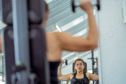Senior woman doing exercises in the gym to stay healthy, trains muscles, workout with weights at the gym.