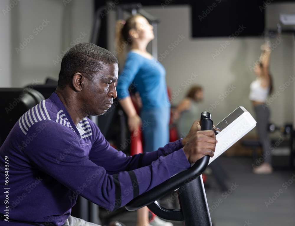 Fototapeta premium African-american man training on exercise bike in gym