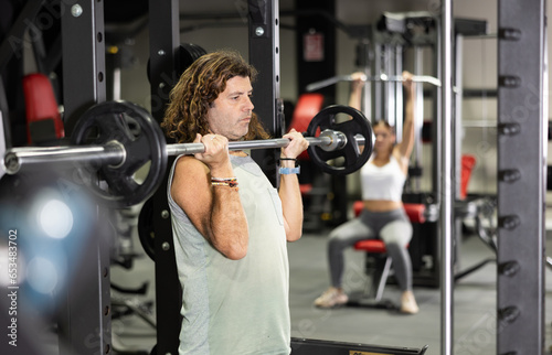 Muscular man doing barbell exercises in the gym