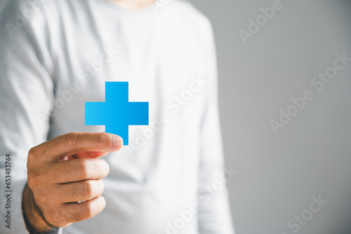 Isolated, a male hand securely holds a plus icon, embodying addition of positives, benefits, personal growth, health insurance, and growth. Emphasizes innovation in health care and technology.