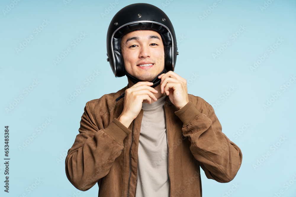 Smiling young asian biker in stylish casual jacket wearing protective helmet looking at camera Smiling young asian biker in stylish casual jacket wearing protective helmet looking at camera