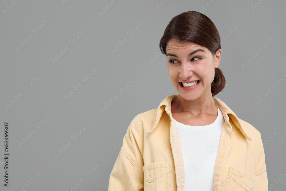 Portrait of embarrassed young woman on grey background, space for text Portrait of embarrassed young woman on grey background, space for text