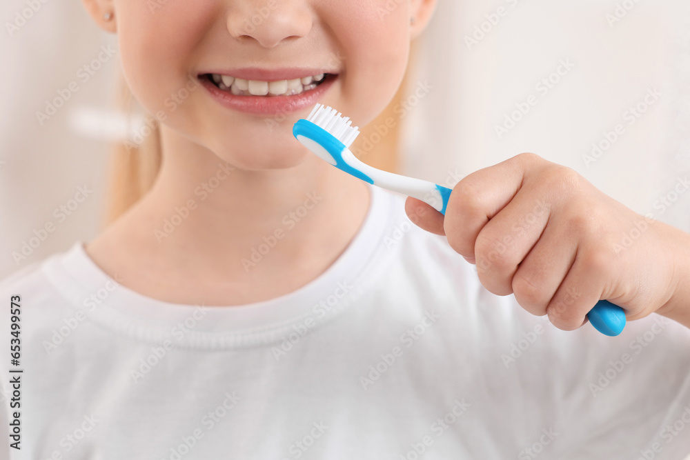 Little girl holding plastic toothbrush indoors, closeup Little girl holding plastic toothbrush indoors, closeup