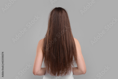 Woman with damaged hair on light grey background, back view