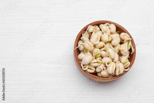Sprouted kidney beans in bowl on white wooden table, top view. Space for text