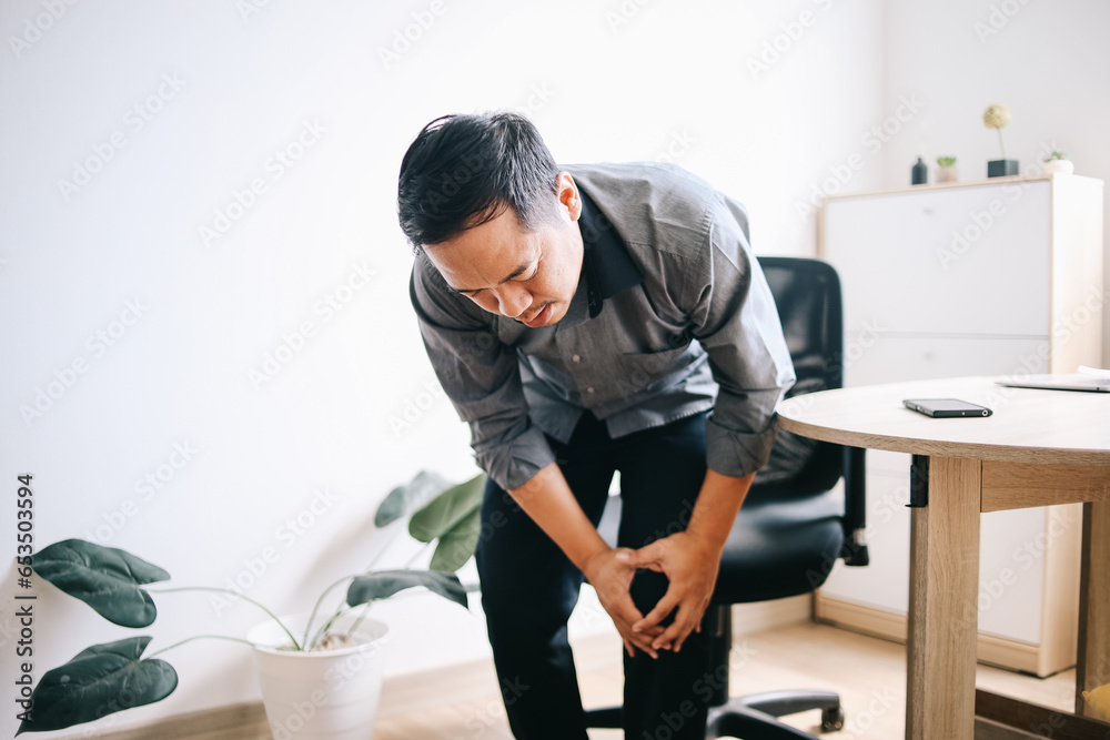 Man suffering from knee pain in workplace Man suffering from knee pain in workplace